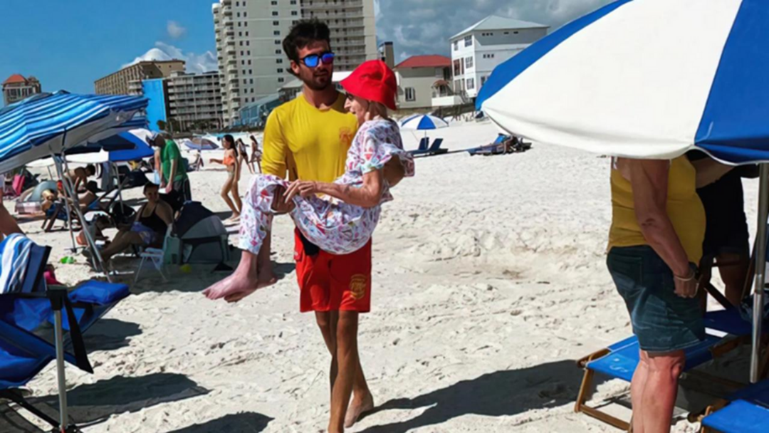 Article heading image for Lifeguards Go Viral For Carrying Elderly Woman To Beach While On Holiday